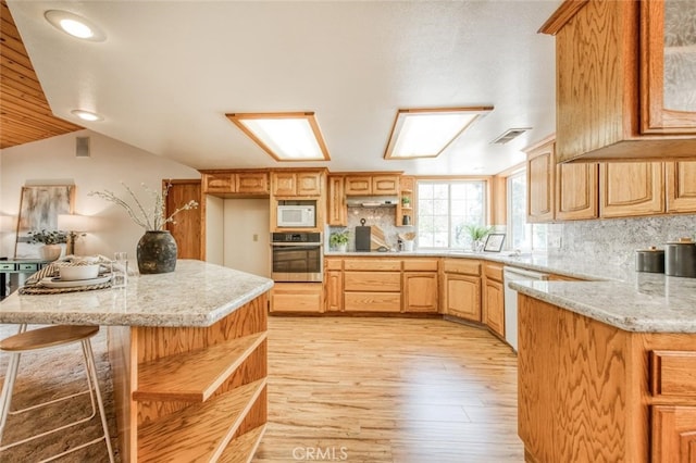 kitchen with light hardwood / wood-style floors, decorative backsplash, light stone countertops, and white appliances