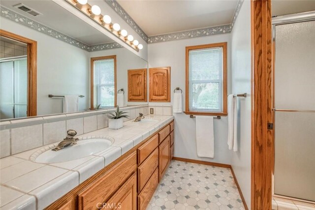 18486 Tollhouse Rd, Clovis, CA 93619 - bathroom with double vanity, a shower with shower door, tile patterned floors, and baseboards