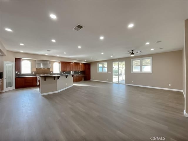 unfurnished living room with baseboards, visible vents, ceiling fan, wood finished floors, and recessed lighting