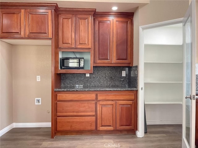 kitchen featuring hardwood / wood-style flooring, dark stone counters, and decorative backsplash