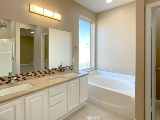 bathroom with a garden tub, backsplash, a sink, and tile patterned floors