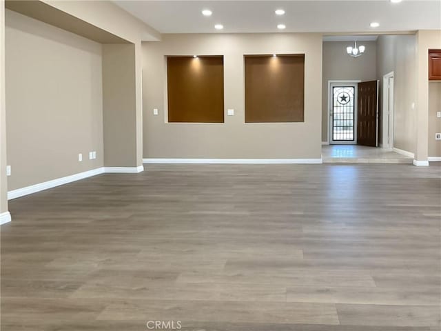 empty room with an inviting chandelier and light hardwood / wood-style flooring