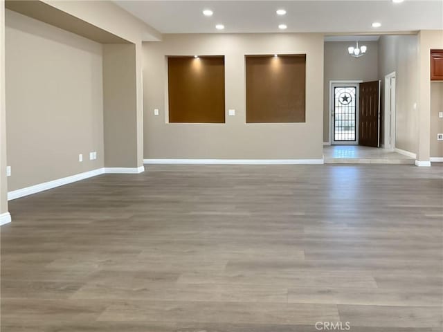 unfurnished room with a chandelier, recessed lighting, light wood-style flooring, and baseboards