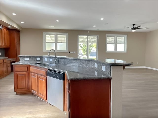 kitchen with a sink, dark stone countertops, stainless steel dishwasher, and an island with sink