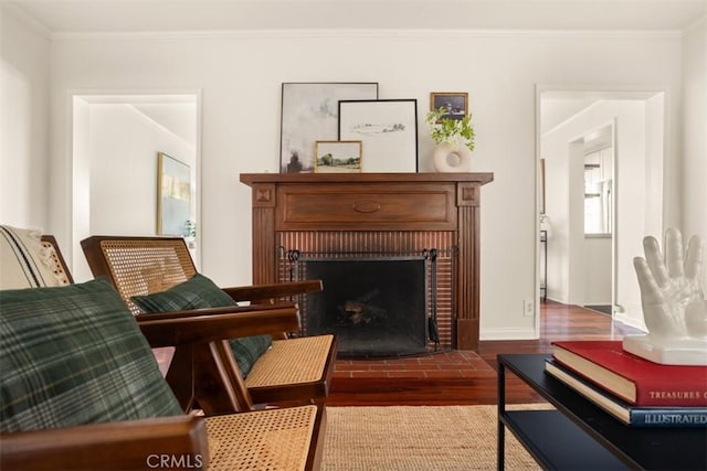 sitting room featuring hardwood / wood-style flooring, ornamental molding, and a brick fireplace