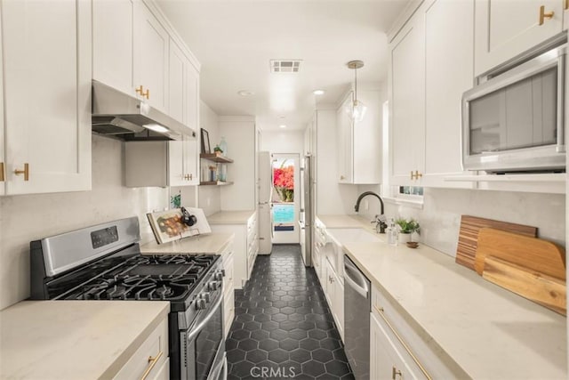 kitchen with appliances with stainless steel finishes, dark tile patterned floors, white cabinetry, and hanging light fixtures