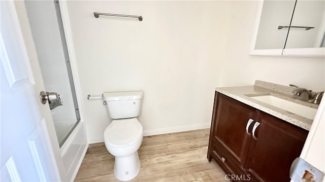 full bathroom featuring vanity, combined bath / shower with glass door, hardwood / wood-style flooring, and toilet