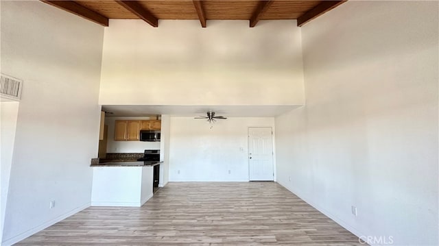 kitchen featuring a towering ceiling, appliances with stainless steel finishes, ceiling fan, wooden ceiling, and light hardwood / wood-style flooring