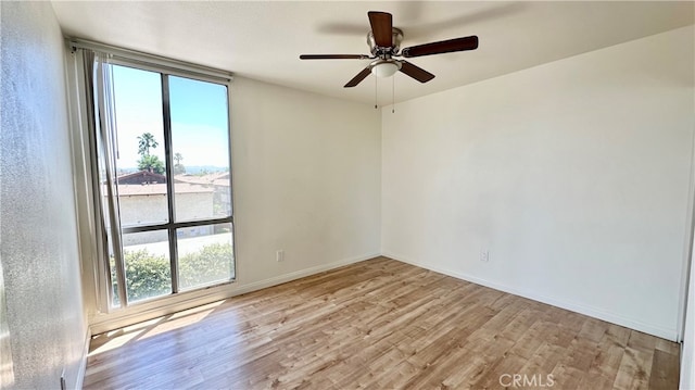 spare room featuring ceiling fan, light wood-type flooring, and a wealth of natural light