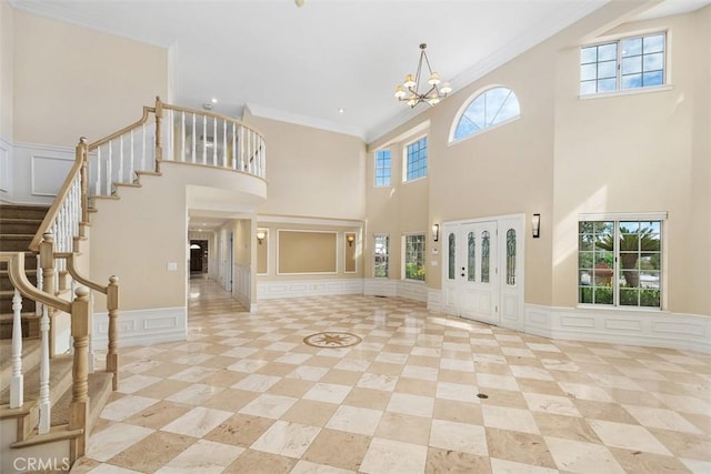 foyer featuring a wealth of natural light, crown molding, a towering ceiling, and a notable chandelier