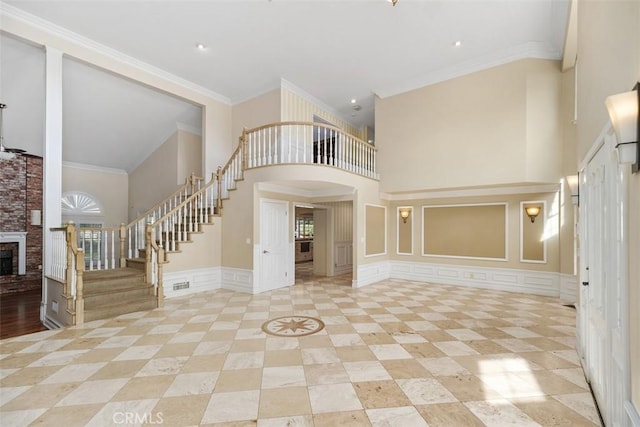 interior space featuring ornamental molding, a towering ceiling, and a brick fireplace