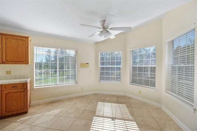 unfurnished dining area featuring ceiling fan and light tile patterned floors