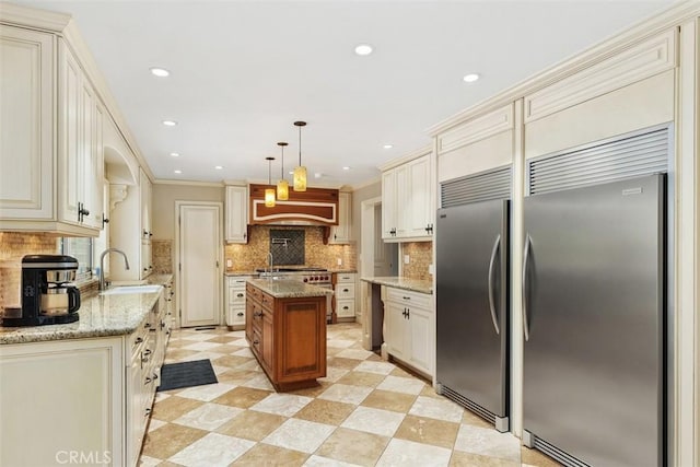 kitchen featuring a center island, sink, light stone countertops, and hanging light fixtures