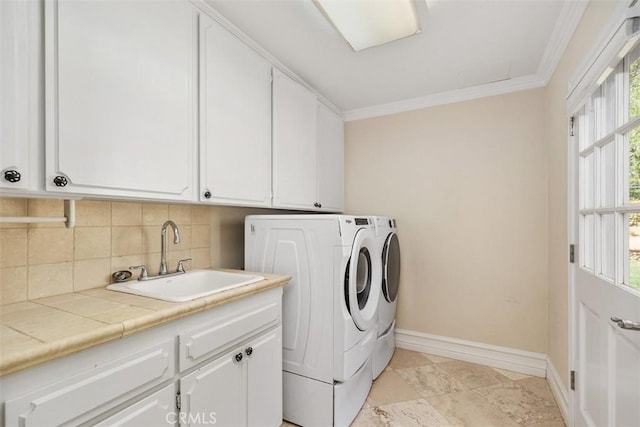 clothes washing area with washer and clothes dryer, crown molding, sink, and cabinets