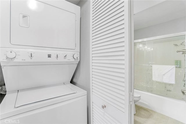 clothes washing area with tile patterned flooring and stacked washer / dryer