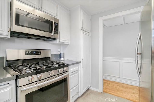 kitchen with light hardwood / wood-style floors, white cabinetry, and appliances with stainless steel finishes