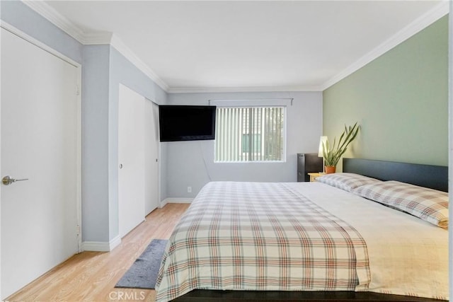 bedroom with light wood-type flooring, ornamental molding, and a closet