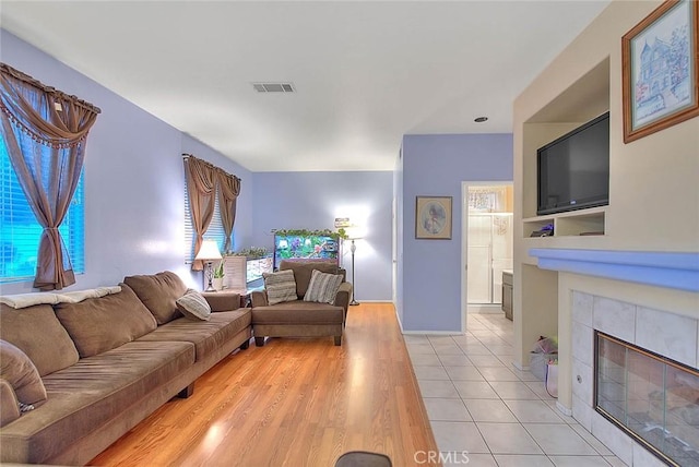 living room featuring a tile fireplace and light wood-type flooring