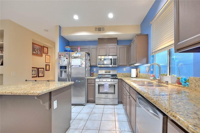 kitchen featuring kitchen peninsula, appliances with stainless steel finishes, a kitchen breakfast bar, sink, and light tile patterned floors