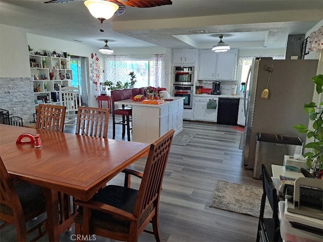 dining space featuring hardwood / wood-style floors and a raised ceiling