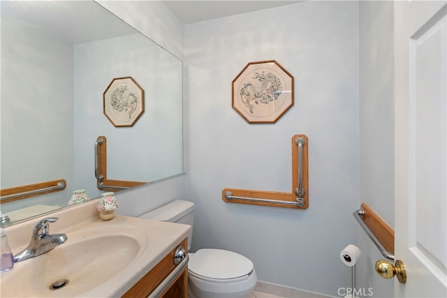 bathroom with toilet, vanity, and tile patterned flooring