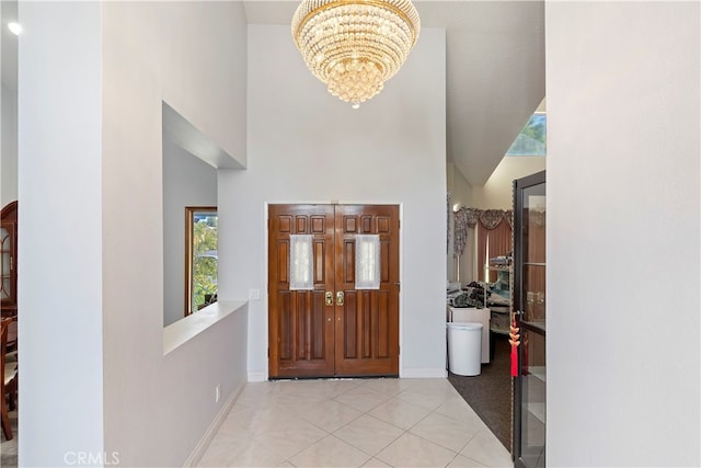 foyer with light tile patterned floors, a notable chandelier, and a high ceiling