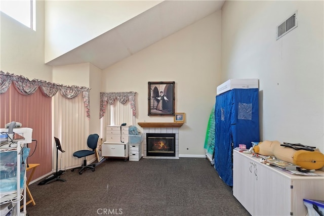 interior space with dark carpet, a tiled fireplace, and high vaulted ceiling