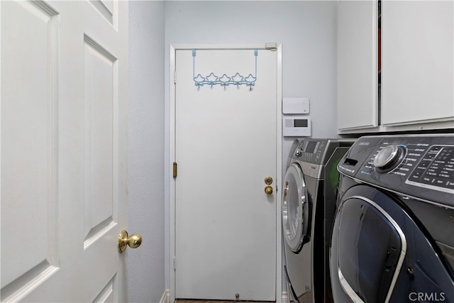 clothes washing area featuring washer and dryer and cabinets