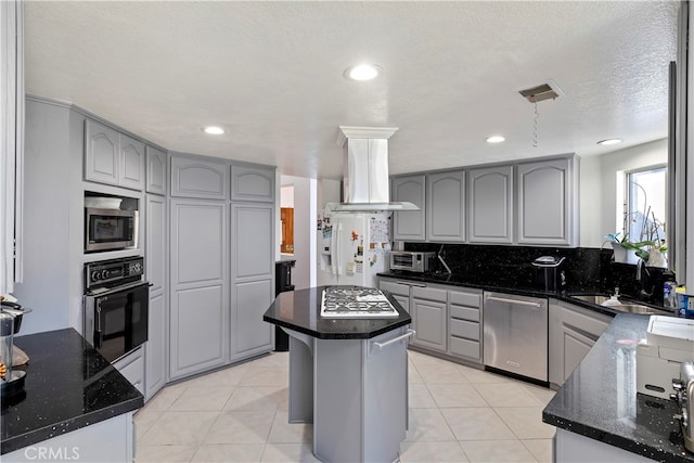 kitchen featuring a kitchen island, a textured ceiling, island range hood, sink, and stainless steel appliances