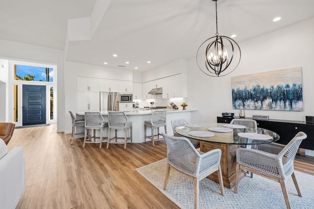 dining area with an inviting chandelier and light hardwood / wood-style flooring