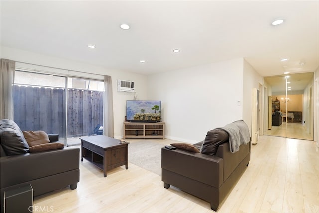 living room with an AC wall unit and light hardwood / wood-style flooring