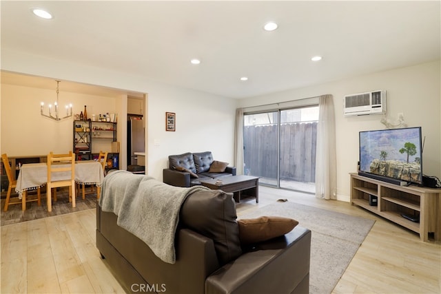 living room featuring light hardwood / wood-style floors, a notable chandelier, and a wall mounted air conditioner