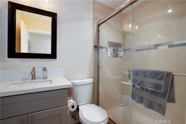 bathroom with a shower with door, vanity, and toilet