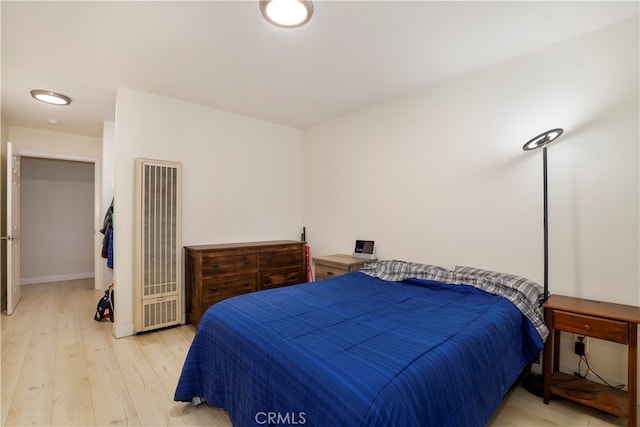 bedroom with heating unit and light wood-type flooring