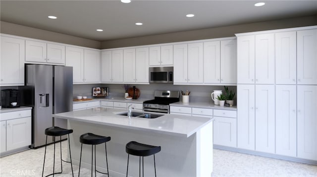 kitchen with a center island with sink, sink, a breakfast bar, white cabinets, and appliances with stainless steel finishes