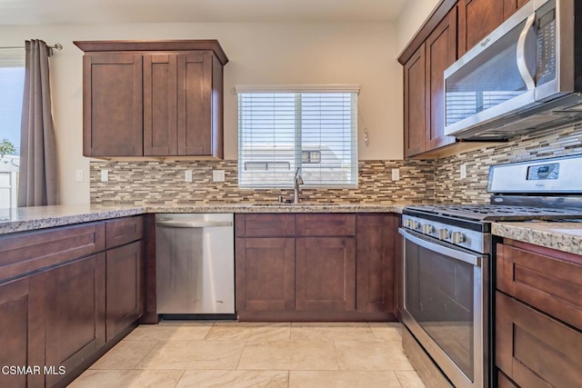 kitchen featuring appliances with stainless steel finishes, light stone counters, and backsplash