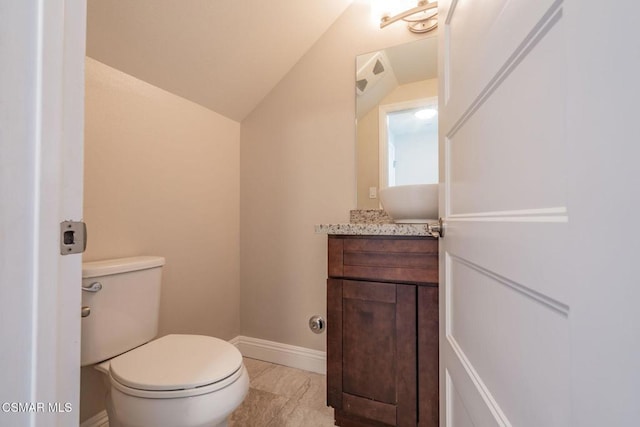 bathroom with vanity, toilet, and vaulted ceiling