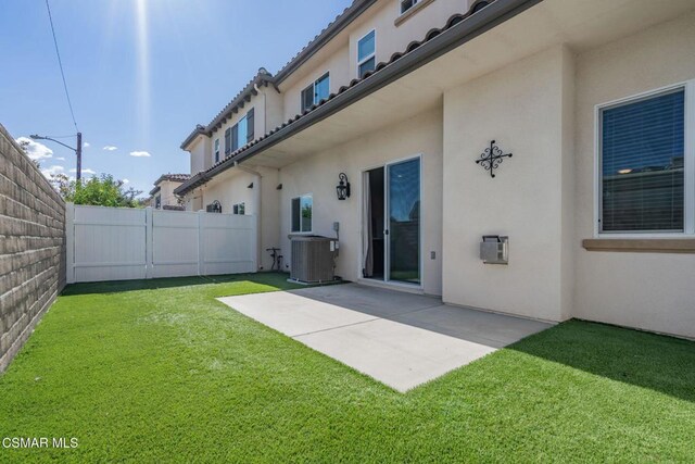 rear view of house featuring a patio, central AC, and a yard