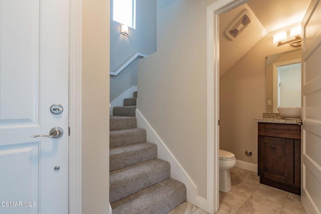 stairway with tile patterned floors and vaulted ceiling