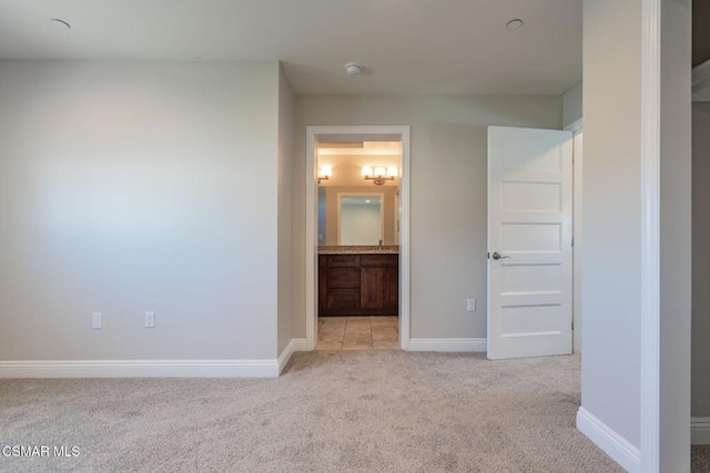 unfurnished bedroom featuring ensuite bath and light colored carpet