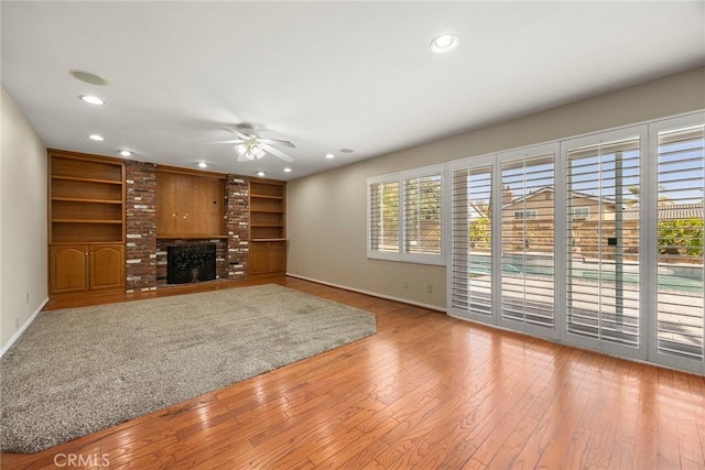 unfurnished living room featuring a fireplace, light hardwood / wood-style floors, and ceiling fan