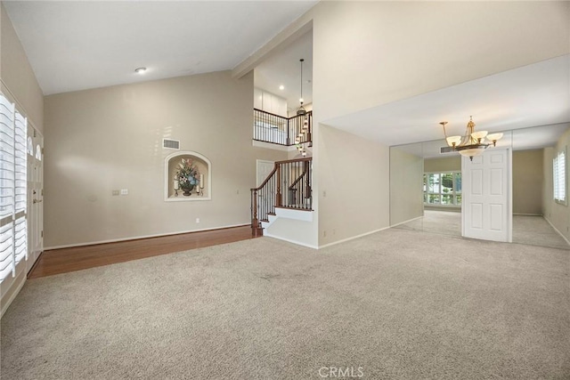 unfurnished living room with vaulted ceiling with beams, a notable chandelier, and light hardwood / wood-style flooring