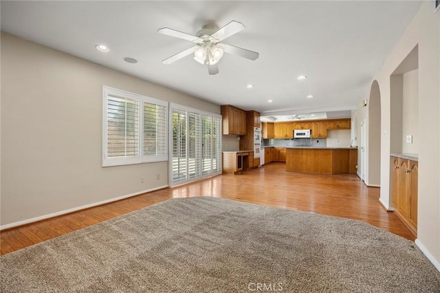 interior space featuring white appliances, ceiling fan, tasteful backsplash, light hardwood / wood-style floors, and kitchen peninsula