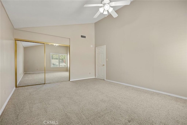 unfurnished bedroom featuring light carpet, a closet, lofted ceiling, and ceiling fan