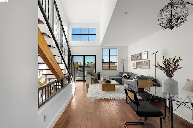 living room with a towering ceiling, wood-type flooring, and an inviting chandelier