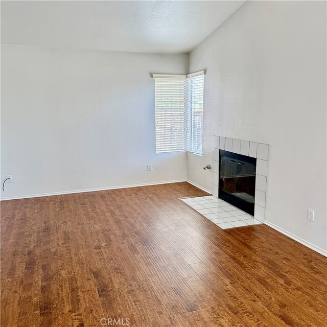 unfurnished living room with a tiled fireplace and light hardwood / wood-style flooring