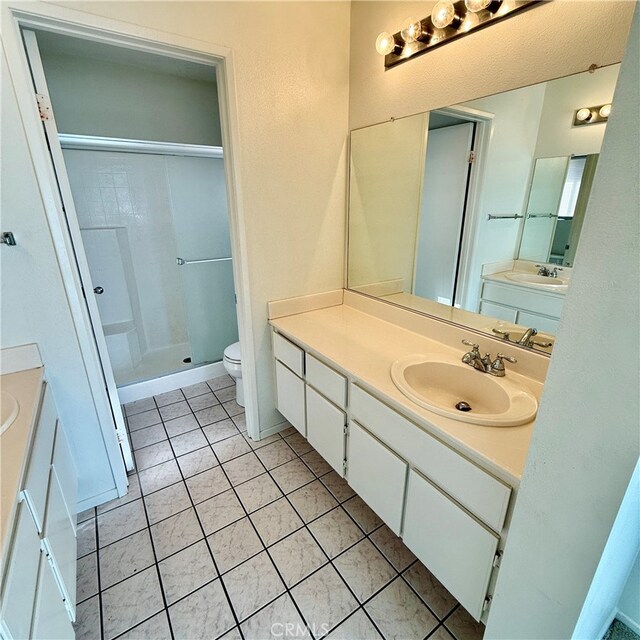 bathroom featuring vanity, a shower, toilet, and tile patterned floors