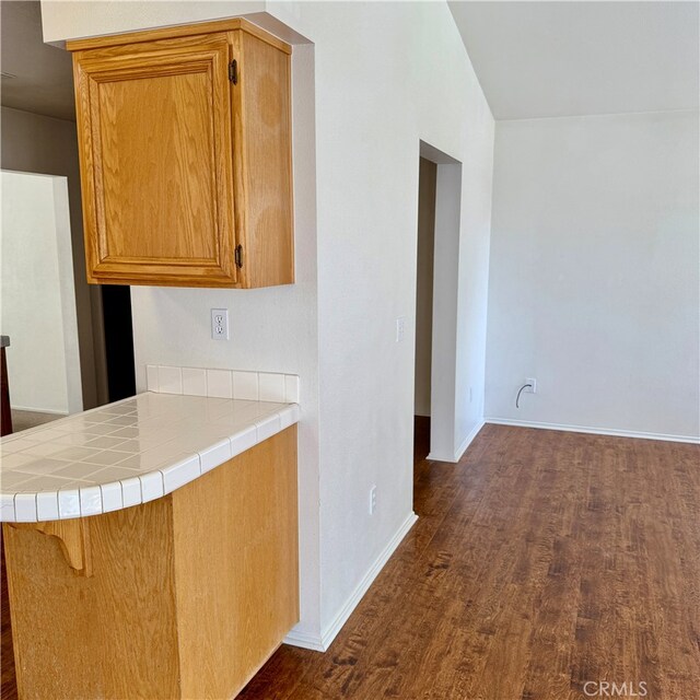 kitchen featuring dark hardwood / wood-style flooring, kitchen peninsula, and tile counters