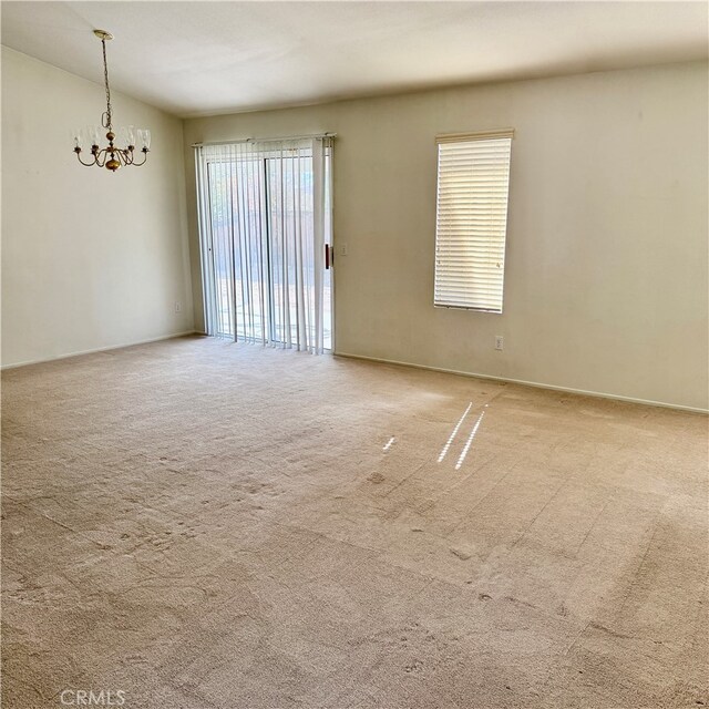 carpeted spare room with a notable chandelier