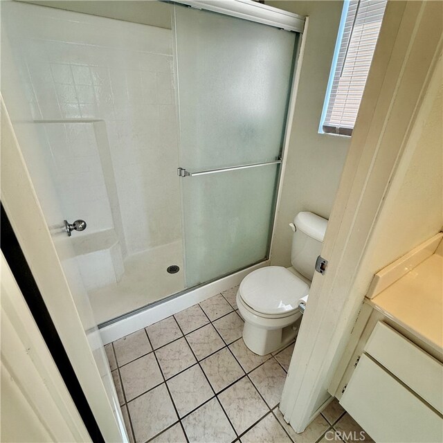 bathroom featuring toilet, tile patterned flooring, vanity, and a shower with door